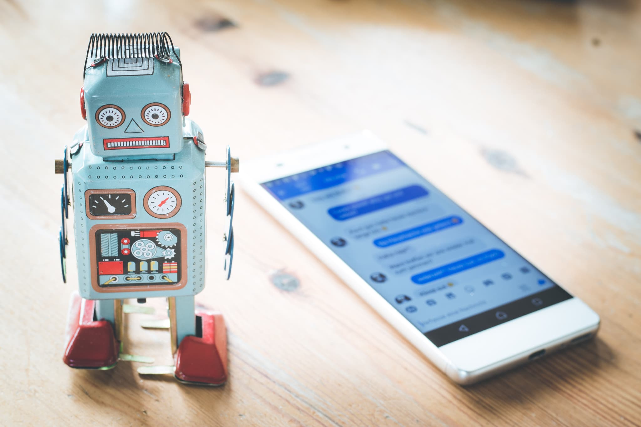 Retro-Roboter neben Smartphone mit Chat-Interface – Werbung in ChatGPT verändert den Kaufmoment