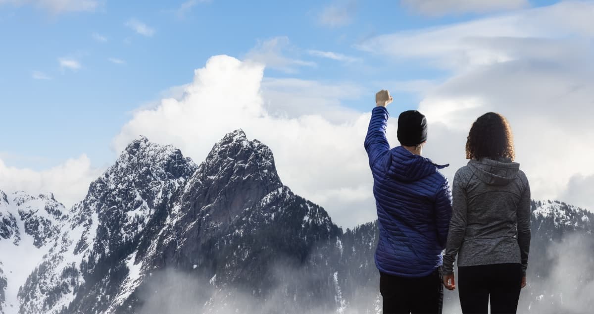 Zwei Menschen blicken auf Berggipfel - Symbol für Partnerschaft und klare Sicht