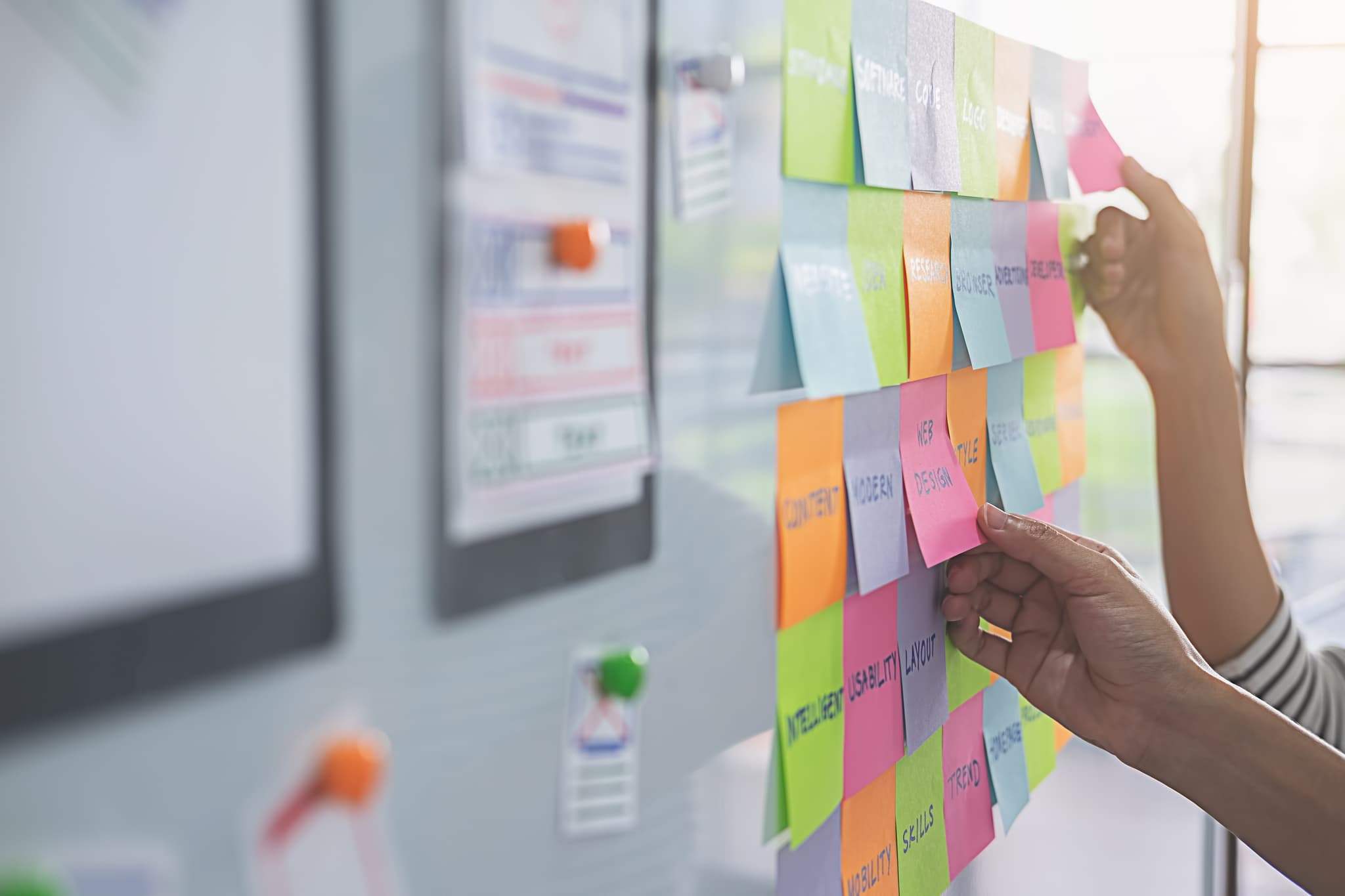 Hand organisiert bunte Post-its für strukturierte Markenarbeit