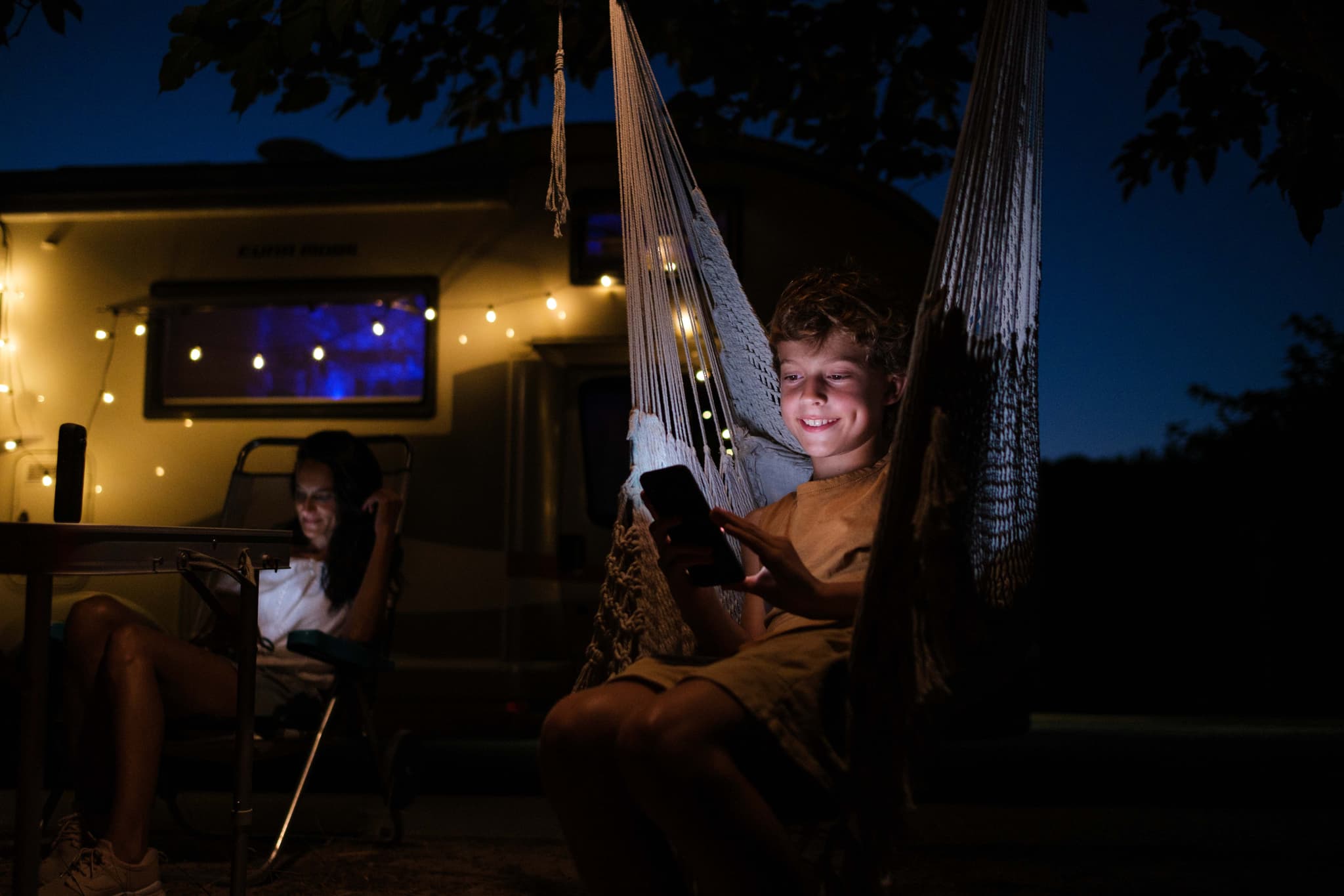 Familie beim Camping nutzt digitale Geräte - generationsübergreifende Community-Teilnahme