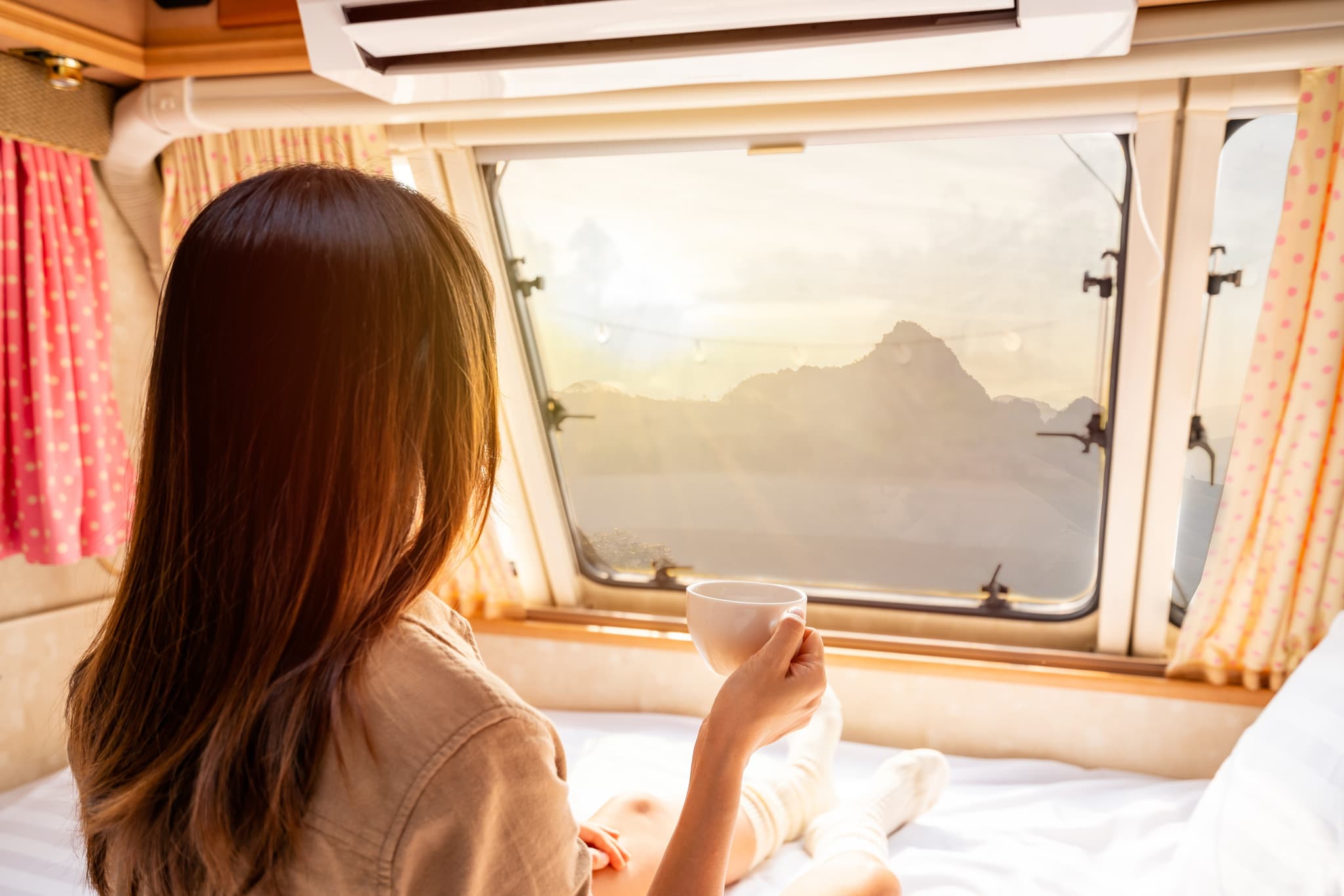 Frau mit Kaffee im Wohnwagen mit Bergblick – Markenarchitektur im Caravan Ökosystem